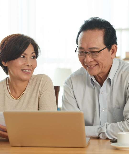 Aged husband and wife using laptop when reviewing bank accounts